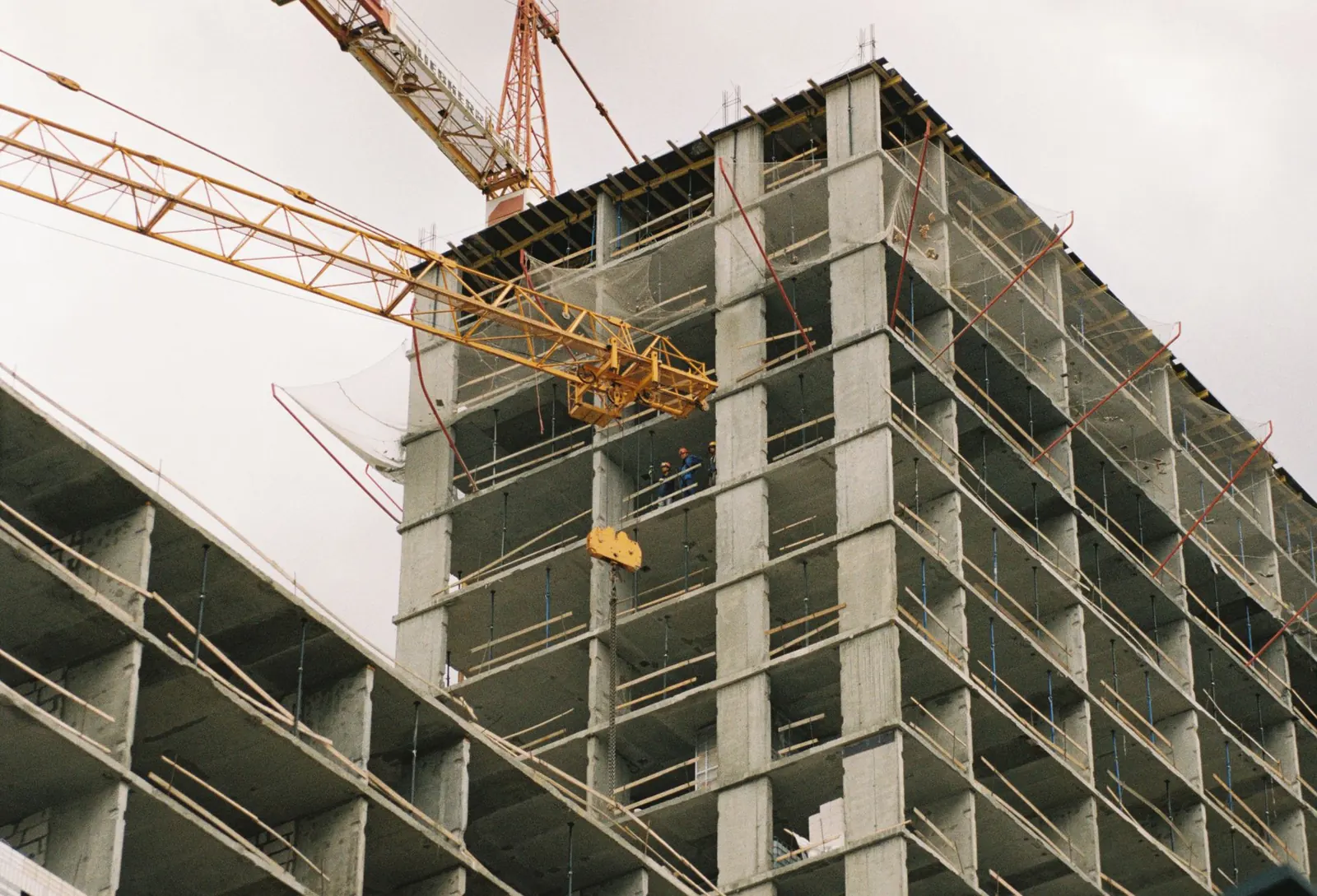 Concrete construction site with cranes, elevated structure, and active trade coordination.